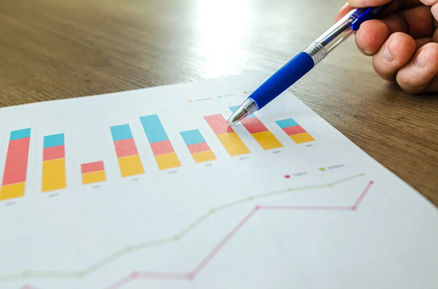 Person analyzing SEO data, pointing to bar charts on paper, highlighting the importance of tracking SEO performance metrics.